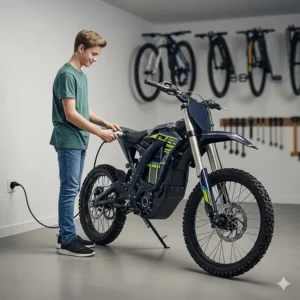 A teenager easily plugging a charging cable into their electric dirt bike at home, demonstrating the simplicity of recharging.