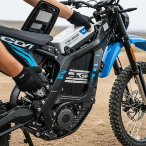 A large, removable lithium-ion battery pack being inserted into the frame of an electric dirt bike, emphasizing the long range and easy swapping capability.
