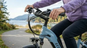 A close-up photograph of a user's hand with limited dexterity operating the ergonomic brake lever on an electric bike, showcasing the light pressure required for safe hydraulic braking with arthritis.