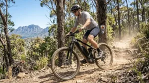 A mountain e-bike climbing a dusty forest trail during the peak of the summer riding season.