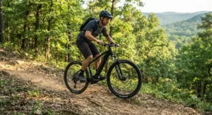 An adventurous mountain biker effortlessly climbing a steep dirt hill using a hardtail emtb under $2000.