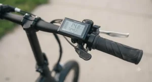 Close-up of the handlebar LCD display and thumb throttle on a quality folding ebike under $1000.
