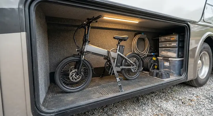 A compact folding electric bike neatly stored inside an RV basement storage compartment folding electric bike for RV travel