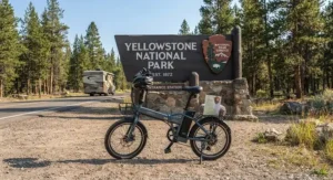 A folding electric bike parked by a National Park entrance sign during an RV road trip