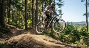 An adventurous rider catching slight air over a dirt jump on an affordable full suspension electric mountain bike.