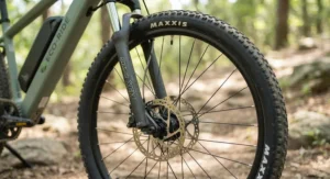 Close-up detail of the front suspension fork and hydraulic disc brakes on an affordable hardtail electric mountain bike.