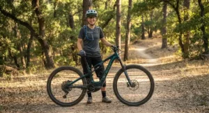 A beginner mountain biker wearing a safety helmet and protective gear standing next to an eMTB.