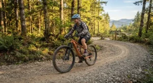 A beginner rider navigating a wide gravel switchback while riding a hardtail eMTB in the afternoon.