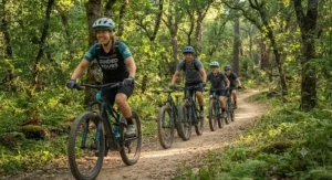 A small group of beginner riders enjoying a guided trail eMTB tour through a green forest.