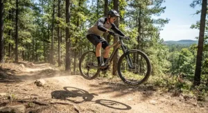 Dynamic action shot of a cyclist catching air over a small dirt jump on a lightweight hardtail electric mountain bike.