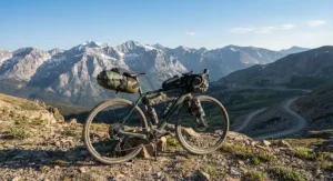 A fully loaded gravel ebike for bikepacking trips parked against a backdrop of a mountain range.
