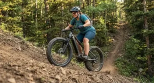 A plus-size rider using a fat tire electric mountain bike with powerful motor assistance to effortlessly climb a steep dirt hill.