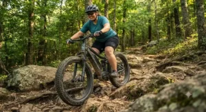 A plus-size rider tackling rocky off-road terrain with the stability and suspension of a fat tire electric mountain bike.