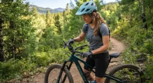 A female mountain biker adjusting the motor display on her trail eMTB before starting her ride.