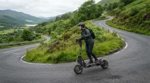 A commuter enjoying dual motor electric scooter hill climbing along a winding mountain highway.