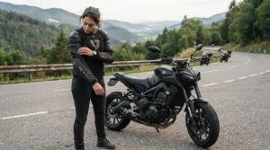 A rider inspecting the reinforced impact zones on a motorcycle riding jacket with armor for naked bike riders outside a suburban coffee shop.