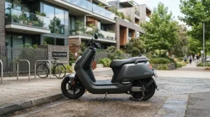 An affordable sport bike style electric moped for adults parked near a modern apartment building